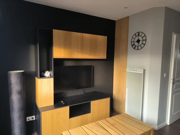 Meuble TV suspendu et rangements intégrés dans un ensemble noir et bois.