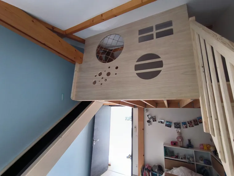 Mezzanine en bois avec découpes circulaires et toboggan.